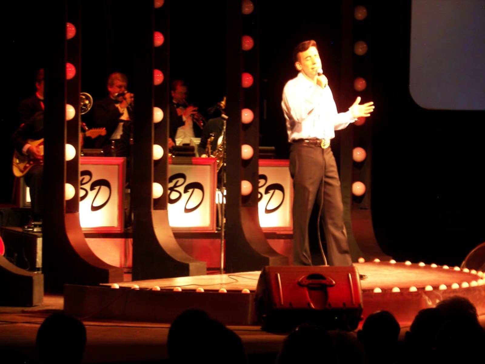 Chaz Esposito singing downstage with the big band behind lit bandstands