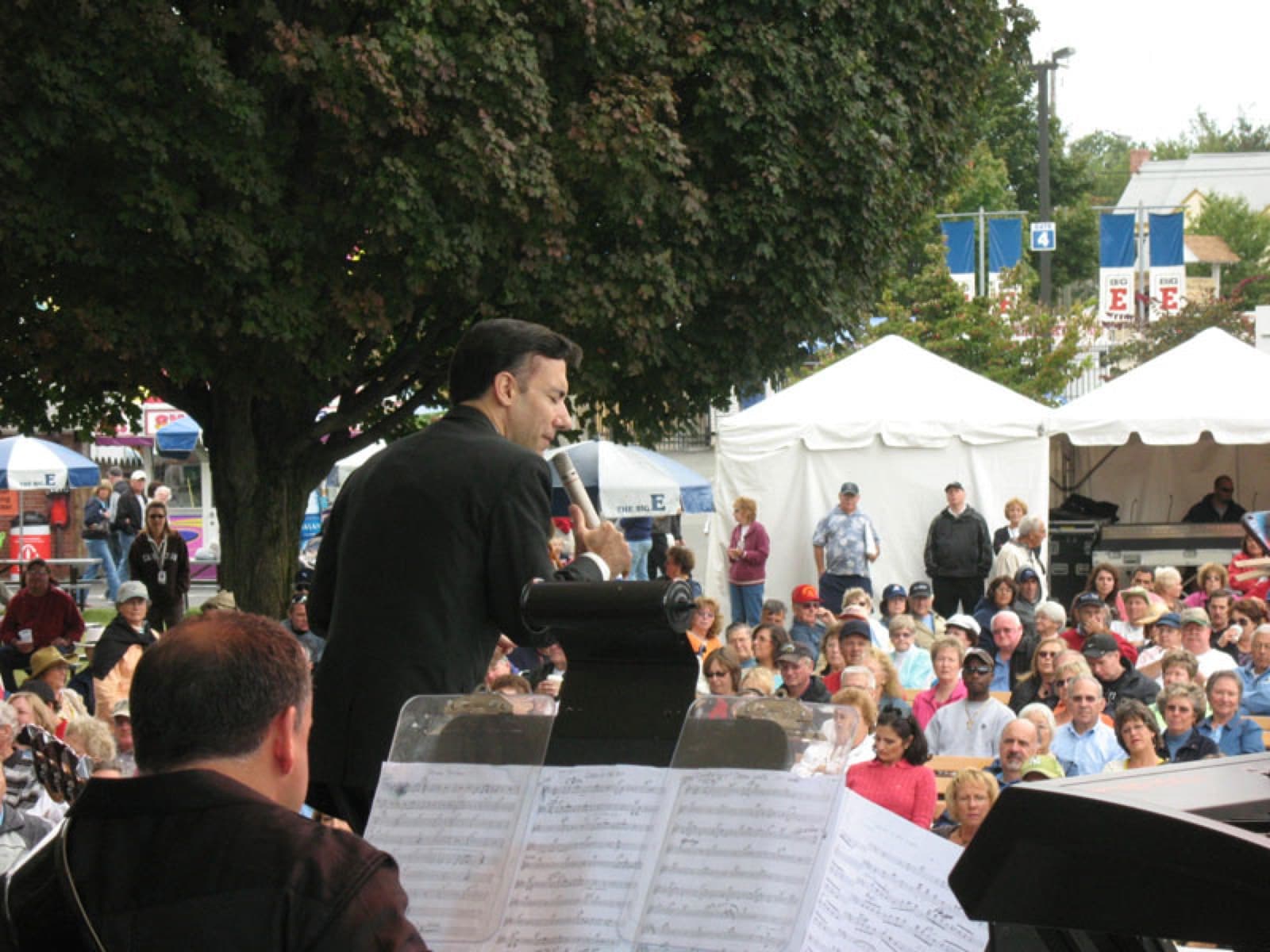 Chaz Esposito seen past the conductor's charts, singing to an outdoor crowd