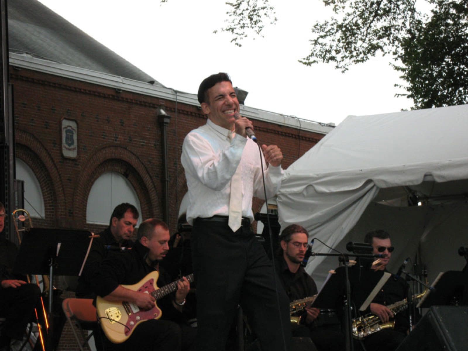 Chaz Esposito laughing with the guitarist and horn section between songs