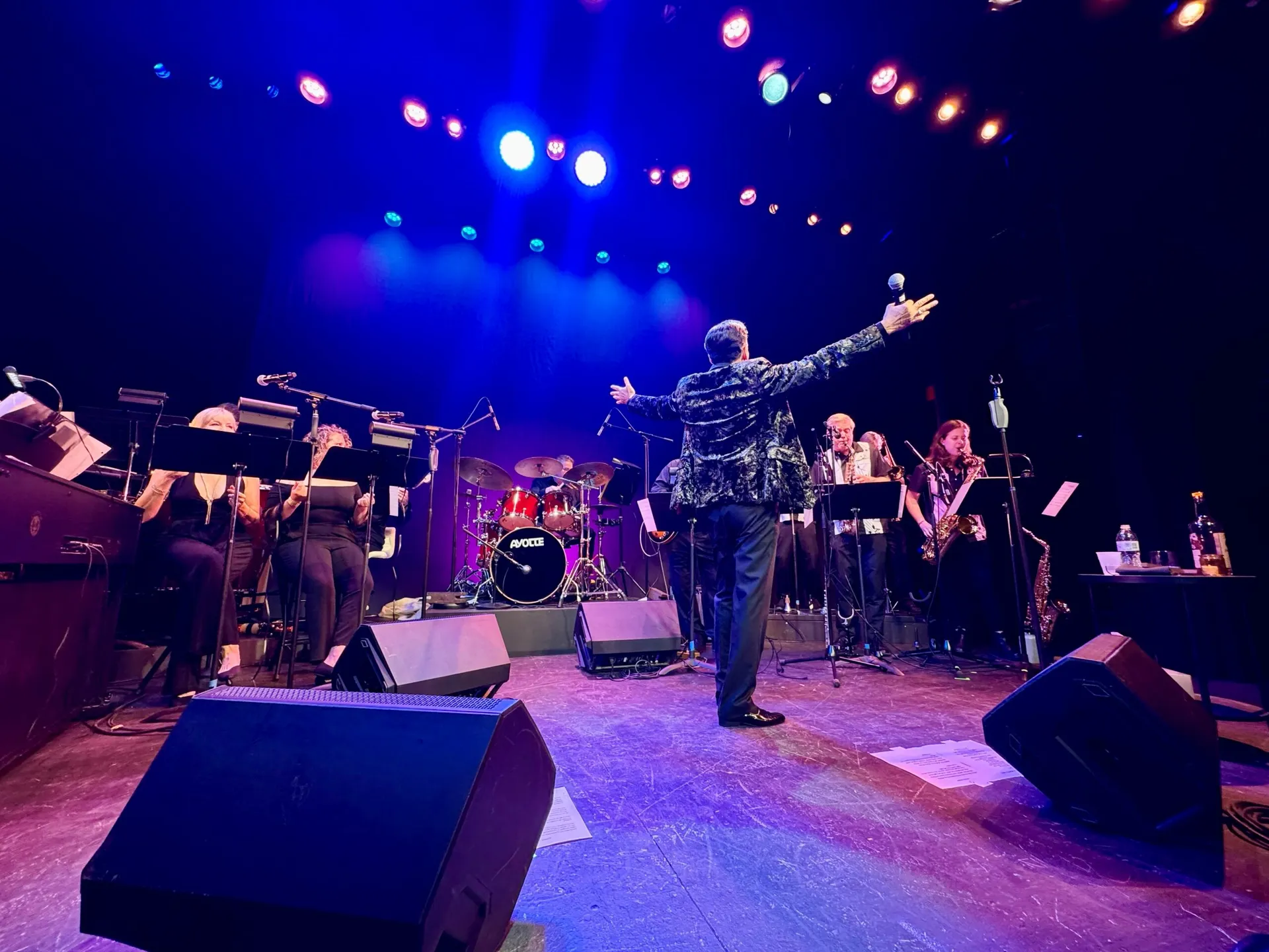 Chaz Esposito, arms spread wide, facing the band from the front of the stage